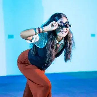 Chica con anteojos inclinada hacia enfrente para ver al público.