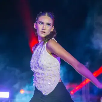 Bailarina a medio movimiento, volteando sobre su hombro con los brazos extenidos hacia abajo.