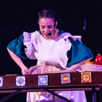 Chica vestida con mandil blanco representando una escena de cocina. 