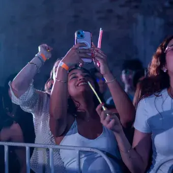 Personas del público recargadas contra vallas, grabando con sus celulares.