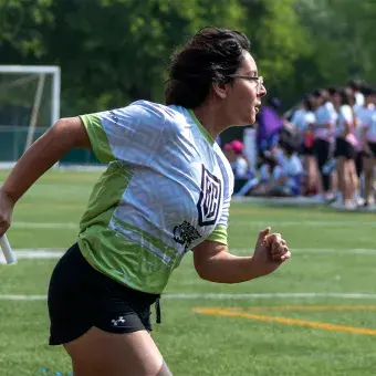 Alumna corriendo con un bastón en atletismo