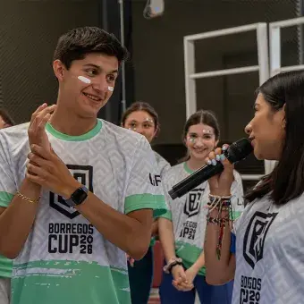 Alumno sonriendo escuchando a la mediadora del juego